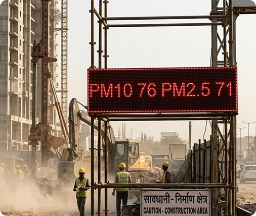 Outdoor LED display board showing live PM1, PM2.5, PM10, PM100, Temperature, Humidity, Pressure readings at a Ahmedabad construction site